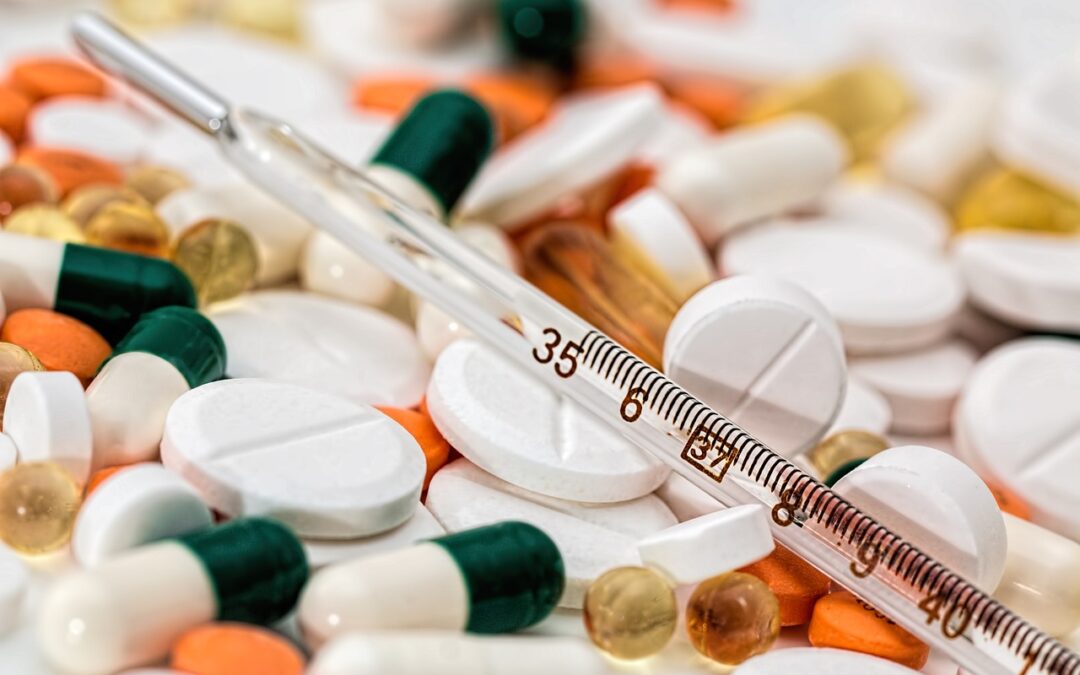 Image of a thermometer placed on top of a pile of pills