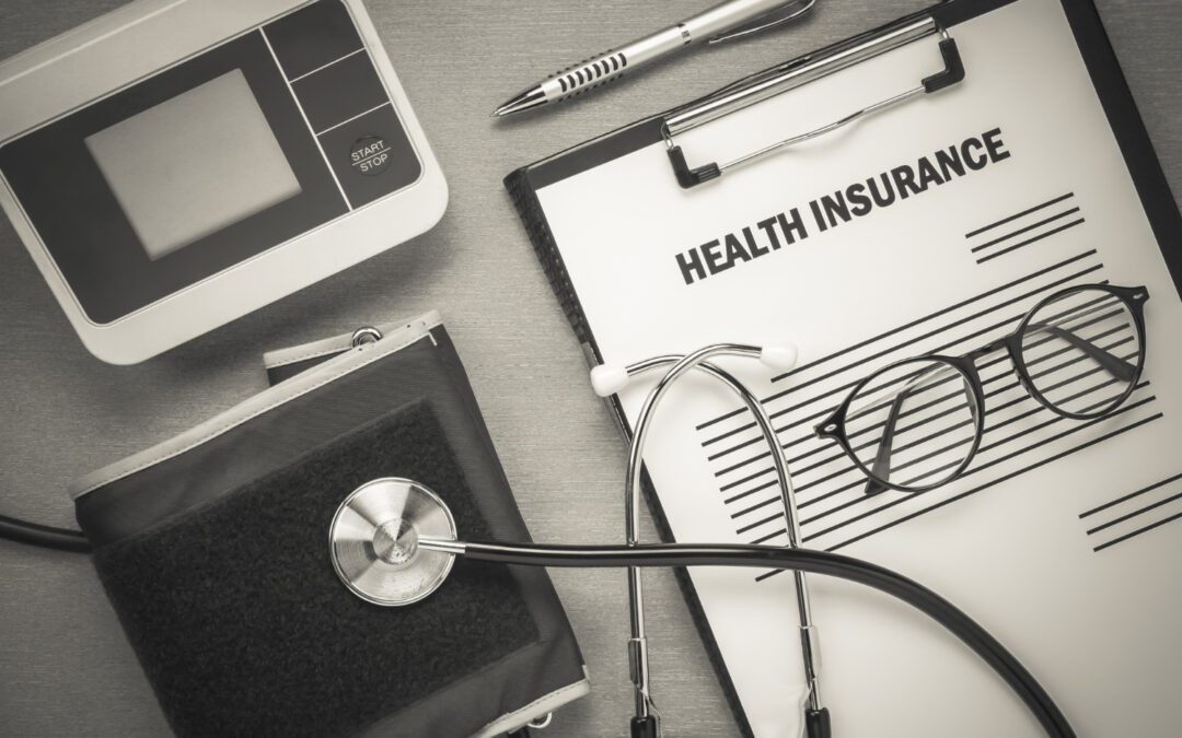 A clipboard with the word Health Insurance written and a stethoscope on it.