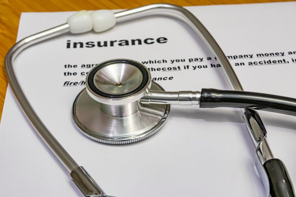 A stethoscope on top of a health insurance paper.