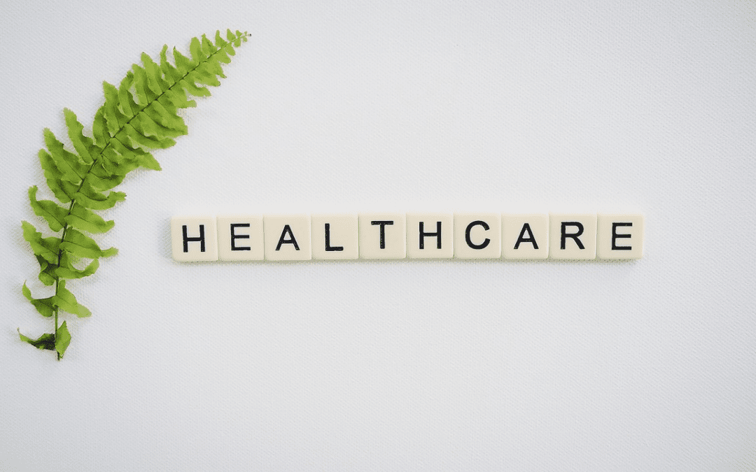 Scrabble tiles spelling "healthcare" with a fern leaf.